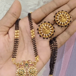 Traditional Maharashtrian mangalsutra with gold-plated pendant featuring multicolored stones and black beads, paired with matching sunburst-design earrings, displayed on a hand.